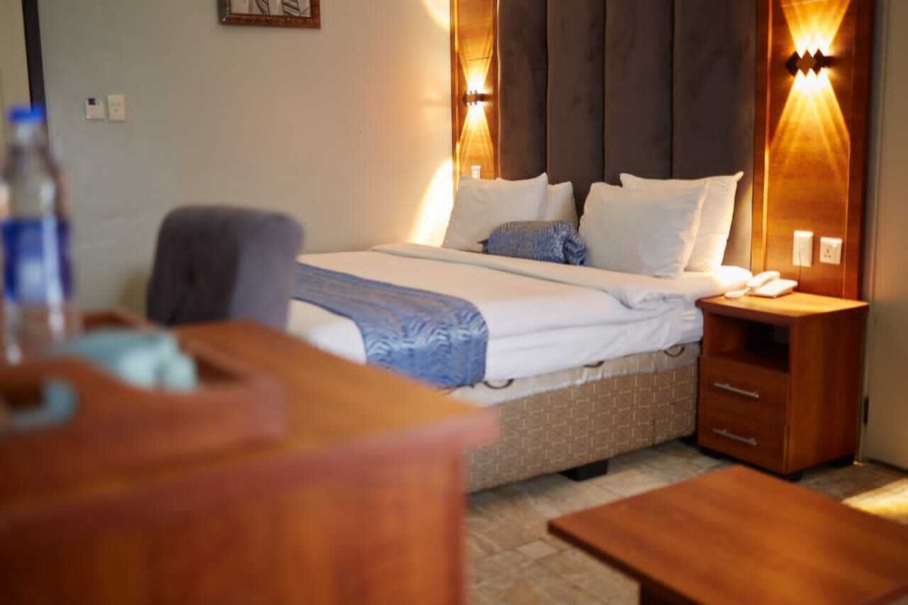 A neatly arranged hotel room with a bed, bedside tables, and a desk.