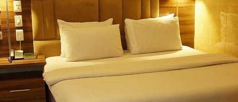 A neatly made bed with a headboard, a bedside table with a lamp, and a patterned rug.