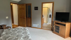 Ein Schlafzimmer mit einem großen Bett, einem Fernseher auf einem Holzboden und einem Schrank mit Schiebetüren.