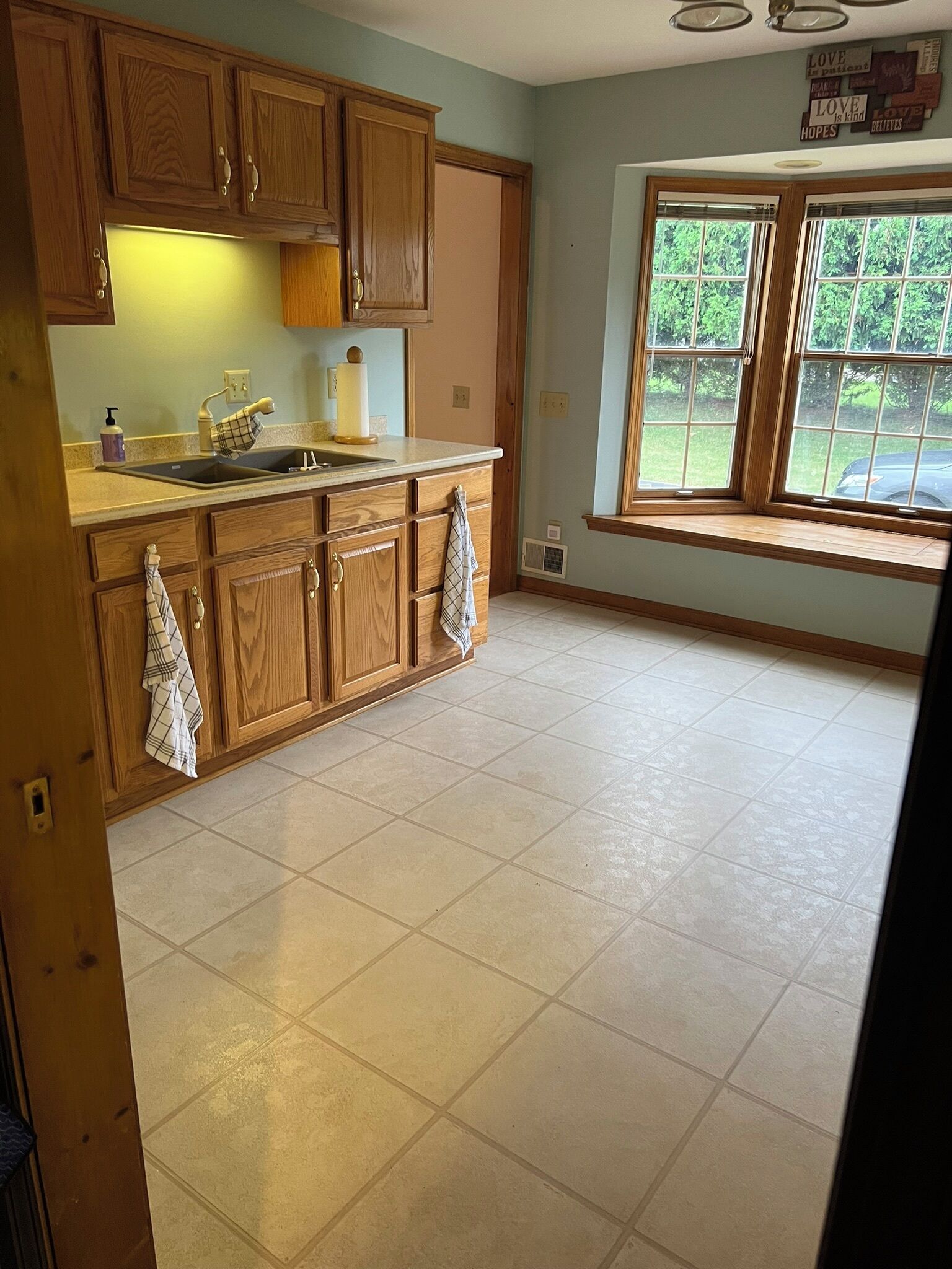 Una cocina con armarios de madera, un lavamanos y una ventana con vistas a zonas verdes.
