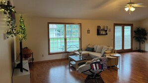 Ein geräumiges Wohnzimmer mit Holzboden, einer Couch, einem Couchtisch und einem Deckenventilator.