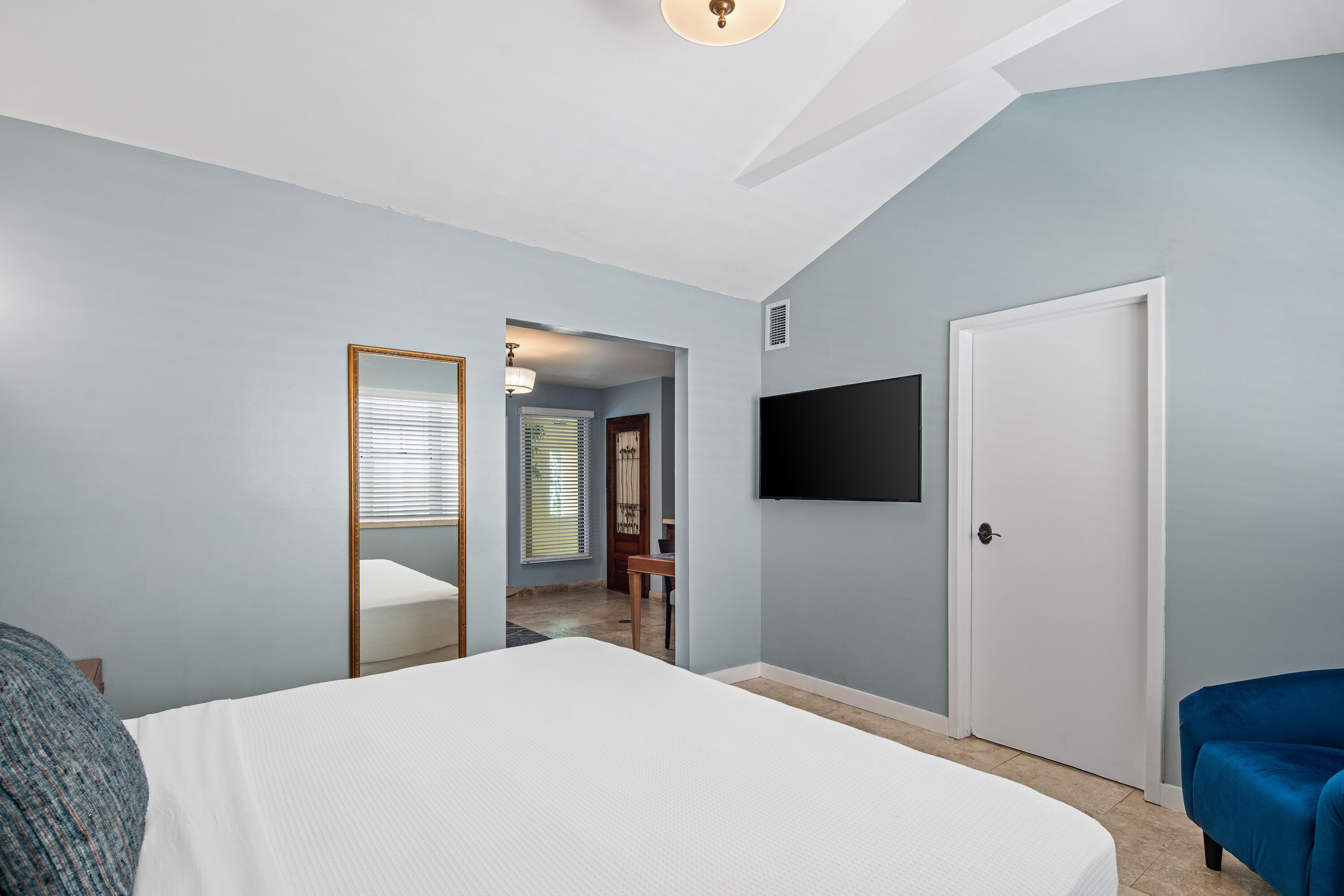 Una camera da letto con un letto, una TV a parete e una porta che conduce in un'altra stanza.