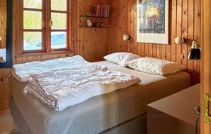 A wooden room with a bed, a window, a shelf with books, and a painting on the wall. - 3 bedroom nice home in Farsø (Farsø)