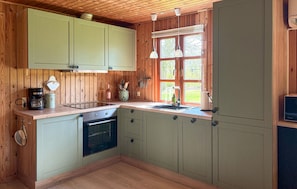 Une cuisine avec des meubles en bois, une cuisiniÚre, un évier et des luminaires suspendus.