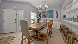 A dining room with a wooden table, chairs, and a chandelier. - Dunes #205 | Remodeled Condo • Community Pool • 1 Min Walk to Beach (South Padre Island)