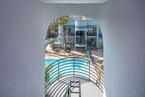 A modern building with a pool, a staircase, and a palm tree.