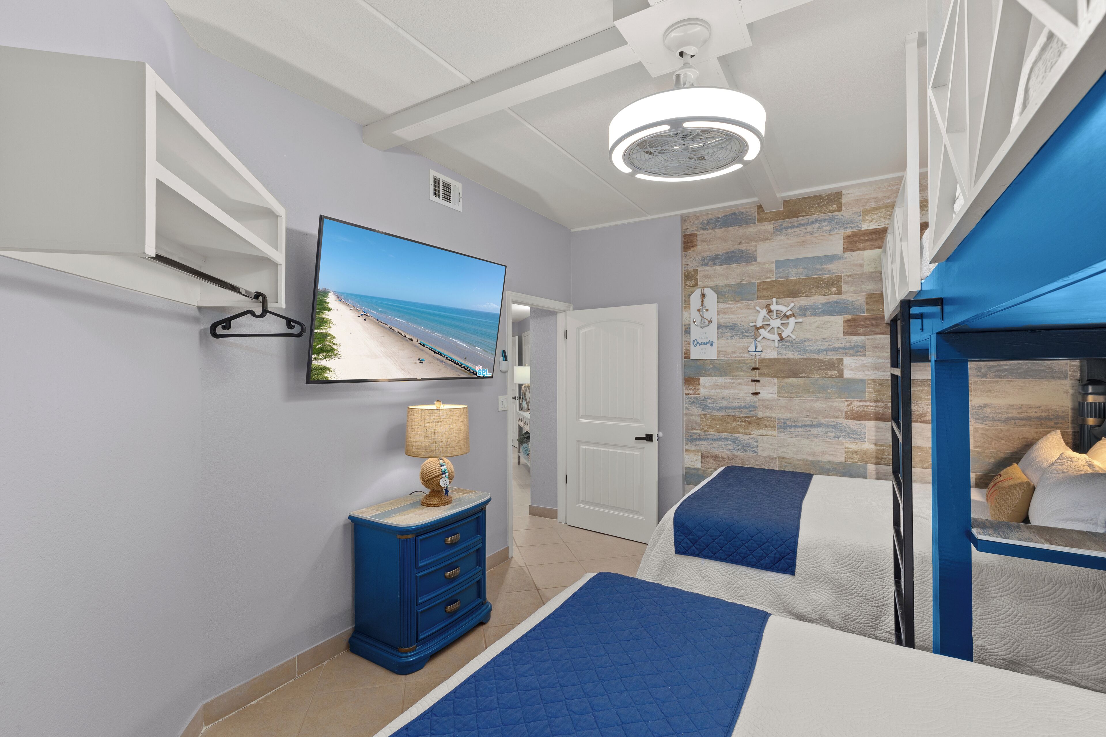Een slaapkamer met twee bedden, een televisie, een dressoir en uitzicht op het strand.