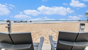 Een strand met twee lege stoelen gericht op de zee.