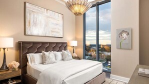 Une chambre moderne avec un grand lit, une vue sur la ville, un lustre et un tableau.