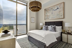 Een moderne slaapkamer met een groot bed, uitzicht op de stad en een groot abstract schilderij aan de muur.