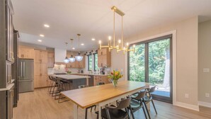 Een moderne keuken met een centraal eiland, hangende lampen en een groot raam met uitzicht op de omgeving.