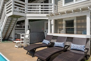 Een zwembadgedeelte met buitenzitplaatsen, een overdekte patio en een trap naar een hoger dek.