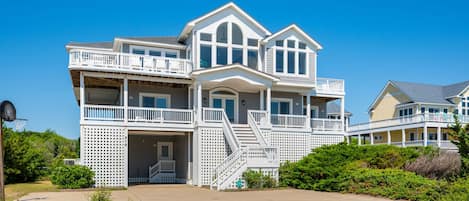 A multi-story house with a balcony, a front porch, and a staircase leading to the entrance.