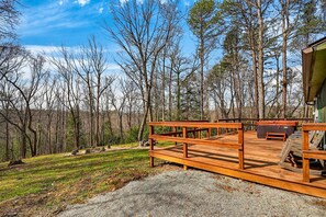 A wooden deck with outdoor seating, surrounded by trees.