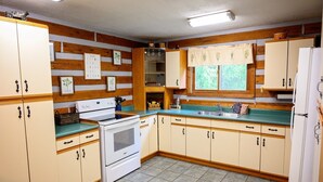 Una cocina con paneles de madera, una estufa, un lavamanos y armarios.
