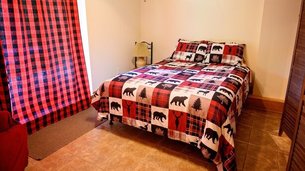 Un dormitorio con una colcha a cuadros, una lámpara, una ventana y una puerta.