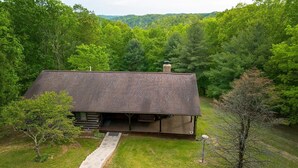 Een chalet met een schuin dak, een schoorsteen en een veranda met treden naar een deur.