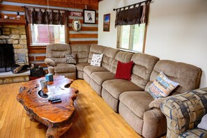 A cozy cabin interior with a sectional sofa, a wooden coffee table, and rustic decor.