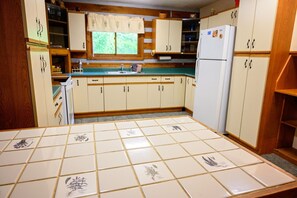 A kitchen with wooden cabinets, a tiled backsplash, and a refrigerator.