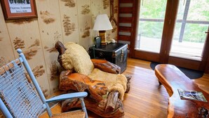 Una habitación rústica con una silla de madera, un banco, una lámpara y una maleta.