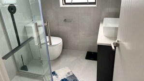 Ein modernes Badezimmer mit Duschkabine aus Glas, Toilette und Waschbecken.