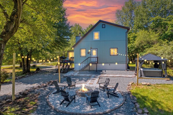 Ein Haus mit Feuerstelle, Sitzgelegenheiten im Freien und Whirlpool.
