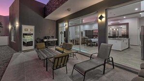 An outdoor patio with seating, a grill, and a view into the kitchen.