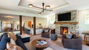 A modern living room with a stone fireplace, a large flat-screen TV, and a cozy seating area. - Abode at Sunny Knob Hill, scenic setting, hot tub (Ketchum)
