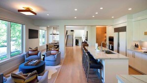 A modern kitchen with a central island, bar seating, and a view of the outdoors. - Abode at Sunny Knob Hill, scenic setting, hot tub (Ketchum)