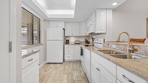 A modern kitchen with white cabinets, granite countertops, a built-in oven, and a stainless steel sink. - Bonita Bay Condo, Beach Club Included! Corner unit! (Bonita Springs)