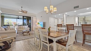 A spacious living room with a dining area, large windows, and a modern kitchen. - Bonita Bay Condo, Beach Club Included! Corner unit! (Bonita Springs)
