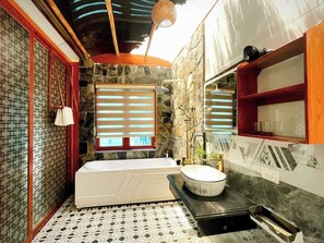 A bathroom with a bathtub, a sink, and a window with blinds.
