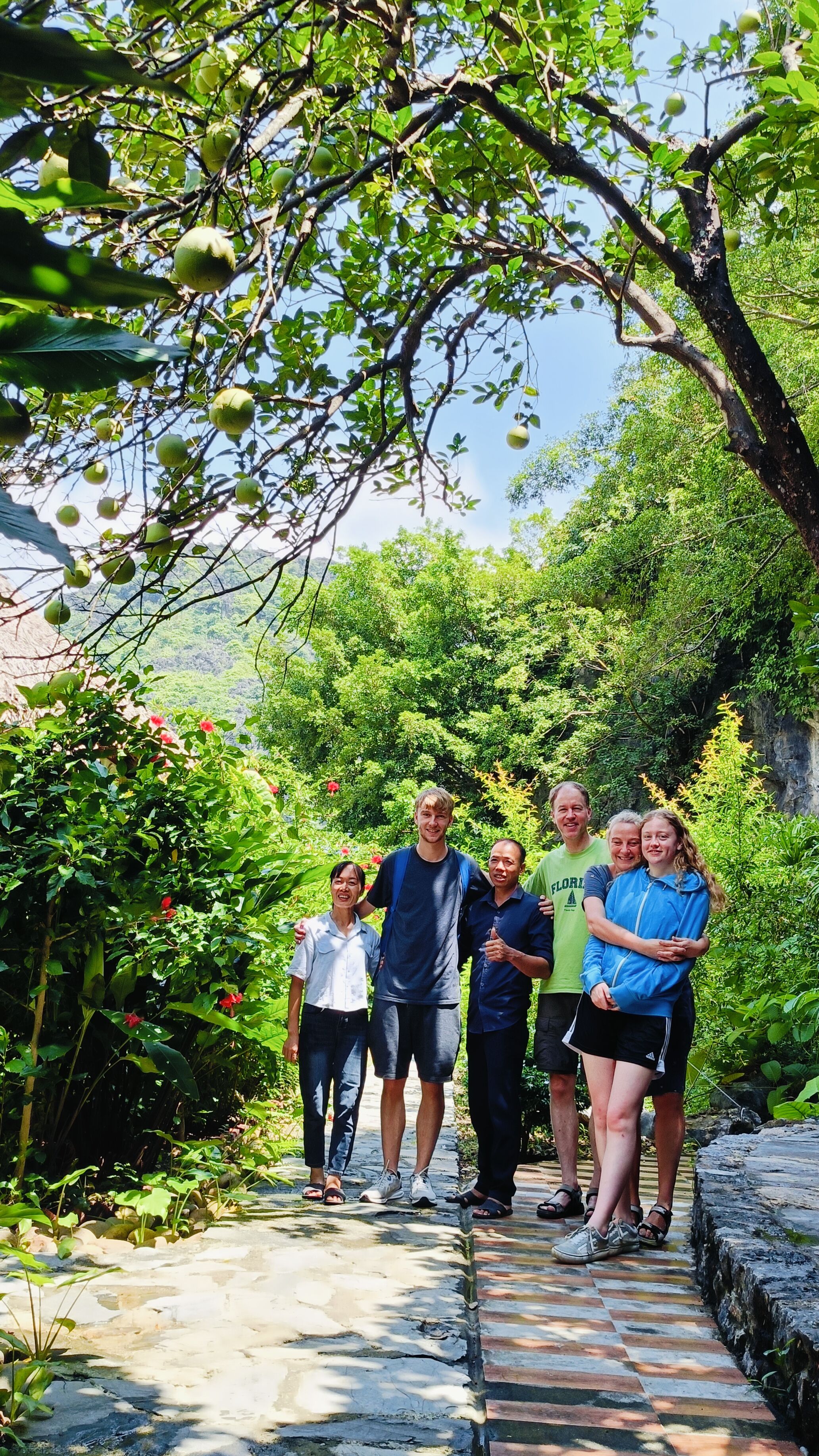 Um grupo de pessoas em um caminho de pedra, cercado por vegetação exuberante e árvores.