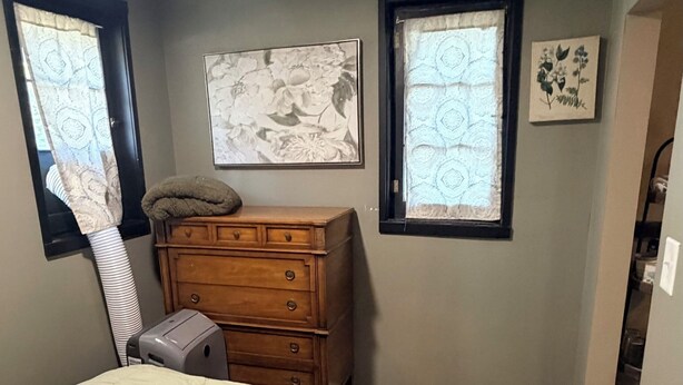 A bedroom with a bed, dresser, two windows, and a door leading to a closet.
