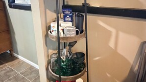 A multi-tiered metal stand with kitchenware and a coffee maker.