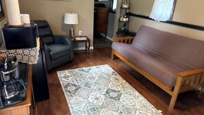 Una sala de estar con un sofá, una mesa de centro, una alfombra y un cuadro en la pared.