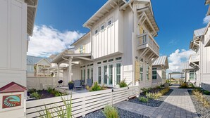 A coastal building with multiple balconies, a covered patio area, and a pathway leading to a gate. - Resort Style Pools, Golf Cart Boardwalk to the Beach (Port Aransas)