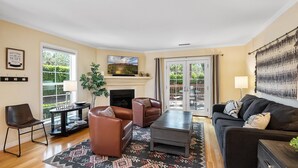 Ein Wohnzimmer mit Kamin, Ledersofas, einem Couchtisch und einem Fernseher.
