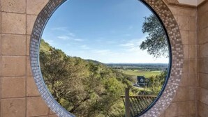 Una ventana circular con vistas a un paisaje montañoso.