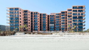 A multi-story hotel with balconies, located near a beach. - Sunrise Delight: Oceanfront Condo w/ Pool Access (New Smyrna Beach)