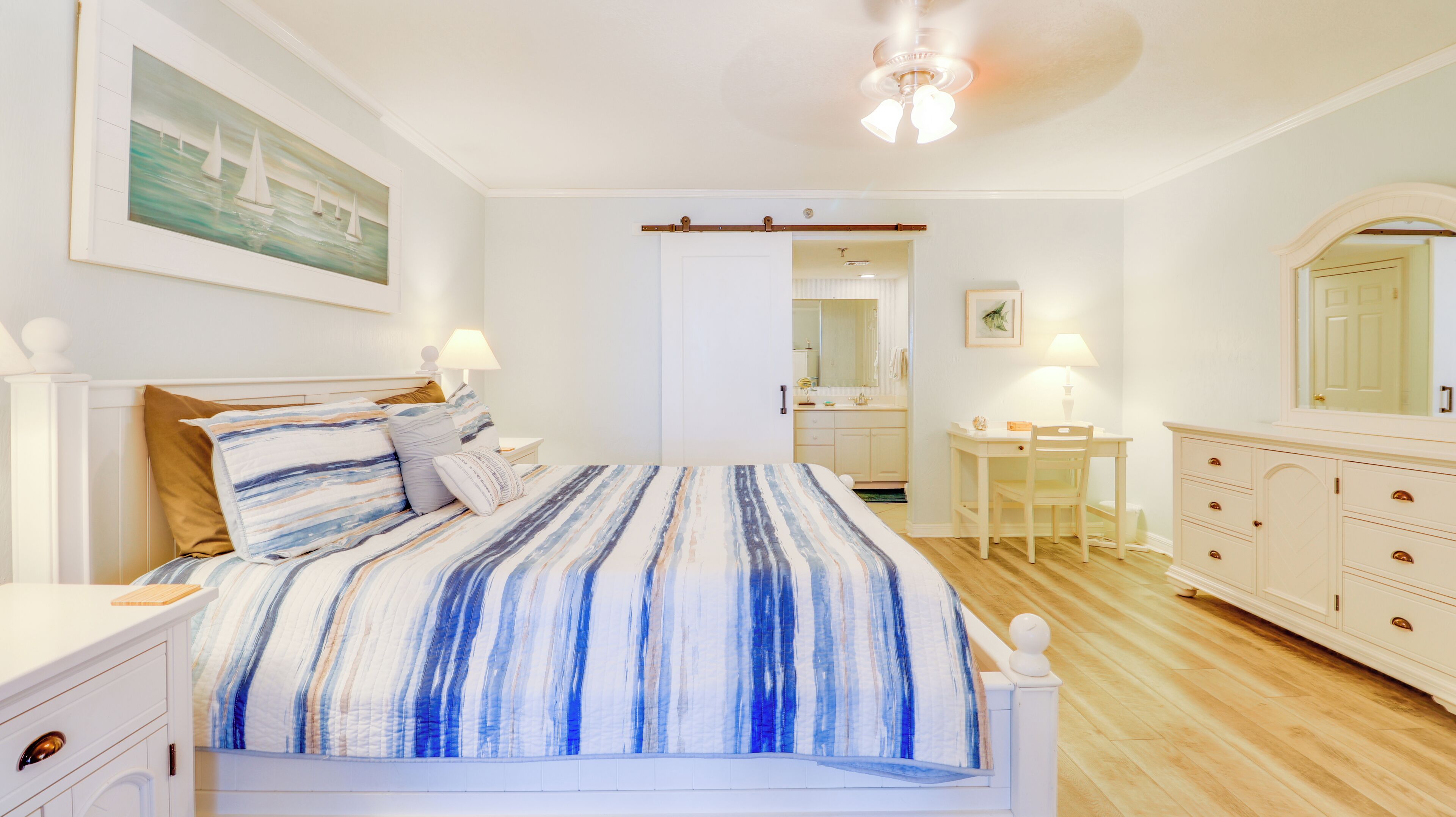 Une chambre à coucher comprenant un lit, des tables de chevet, un bureau et une commode.