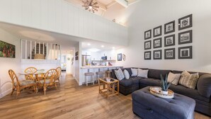 A spacious living area with a dining set, a sofa, and a coffee table. - Breathtaking Condo - Ocean View - Now With AC! (Waikoloa)