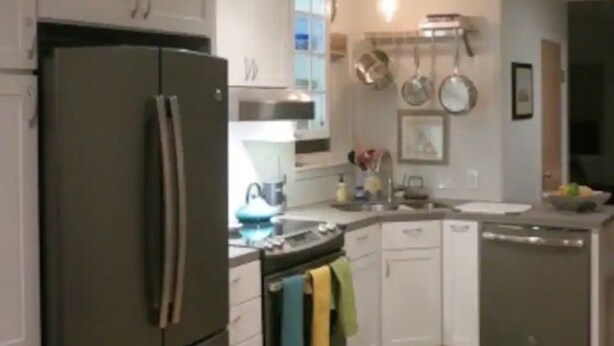 Een moderne keuken met een koelkast, fornuis en vaatwasser. Er zijn kastjes, een spoelbak en een raam.