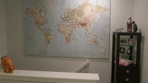 Een wereldkaart aan de muur, een klein plankje met beeldjes, en een witte plank eronder.