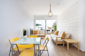 A modern interior with a dining table, chairs, a sofa, and a hanging light fixture. - Home2Book Sunlit Apt Terrace, Las Américas (Playa de la Américas)