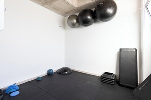 A gym with exercise equipment, including a large black exercise ball, a blue exercise ball, and a blue mat.