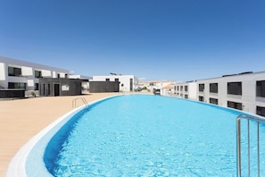 A swimming pool with a clear blue water surface, surrounded by modern buildings with balconies. - Home2Book Stylish Apartment Pool & Terrace Abades (Abades)