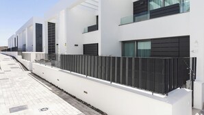 A modern building with white walls, large windows, and a black metal fence. - Home2Book Stylish Apartment Pool & Terrace Abades (Abades)
