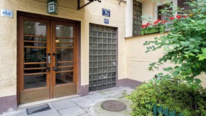 A building with a wooden double door and a window with a metal grid. There is a sign above the door and another on the window. - Old Town Standard Studio (Kraków)