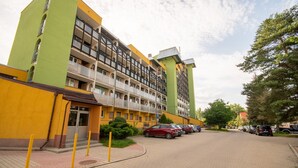 A multi-story residential building with balconies, a parking area, and a paved walkway. - Termy Cieplice Apartment (Jelenia Góra)